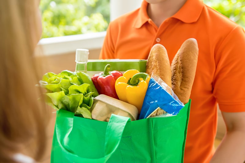 Grocery store delivey man delivering food to a woman at home