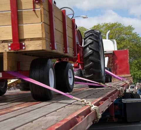 Secured tractor and wagon on a flatbed semi trailer using tie down straps